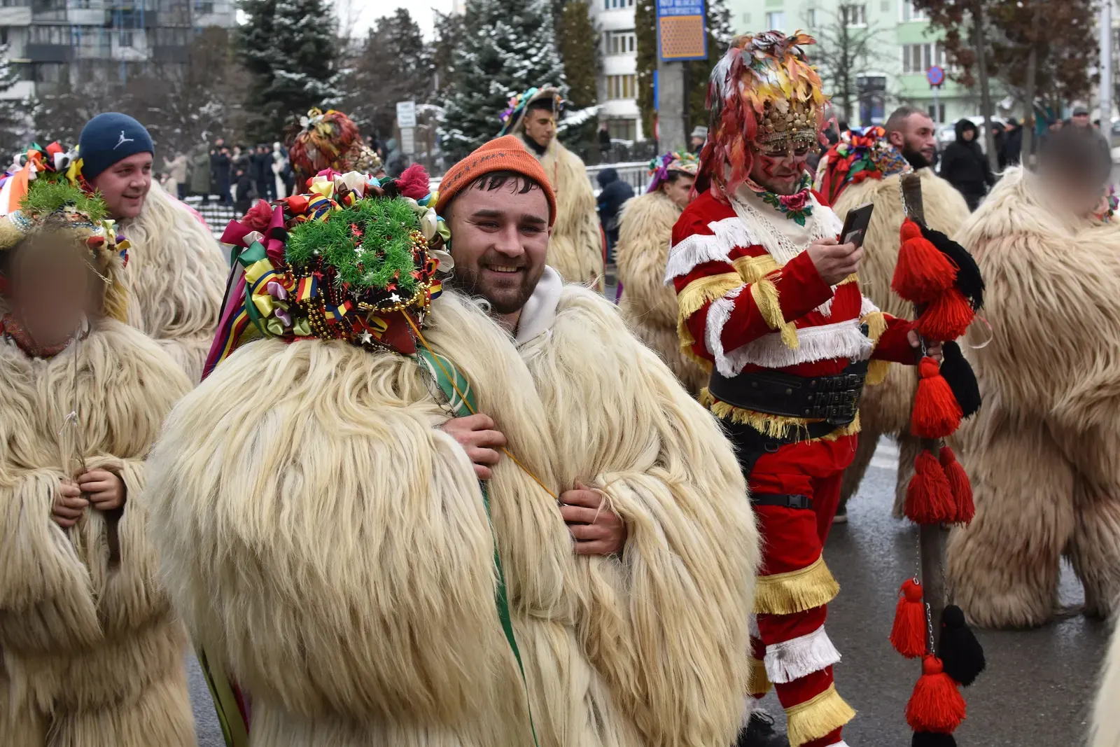 Urători în cojoace lungi din blană albă de oaie, cu căciuli împodobite cu flori, beteală și mărgele, la parada obiceiurilor de iarnă din Suceava, pe 27 decembrie 2025