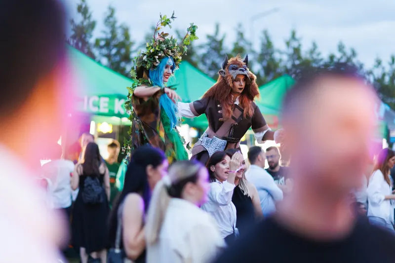 Doi artiști costumați în personaje de basm, deasupra mulțimii de festivalieri, la apus, la Deep in The Forest 2023
