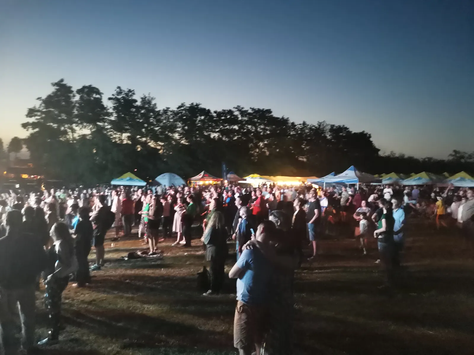Public numeros în picioare pe iarba de pe platoul Cetății de Scaun, la apus, cu corturile standurilor în spate, la Suceava Blues Festival, pe 1 iulie 2022
